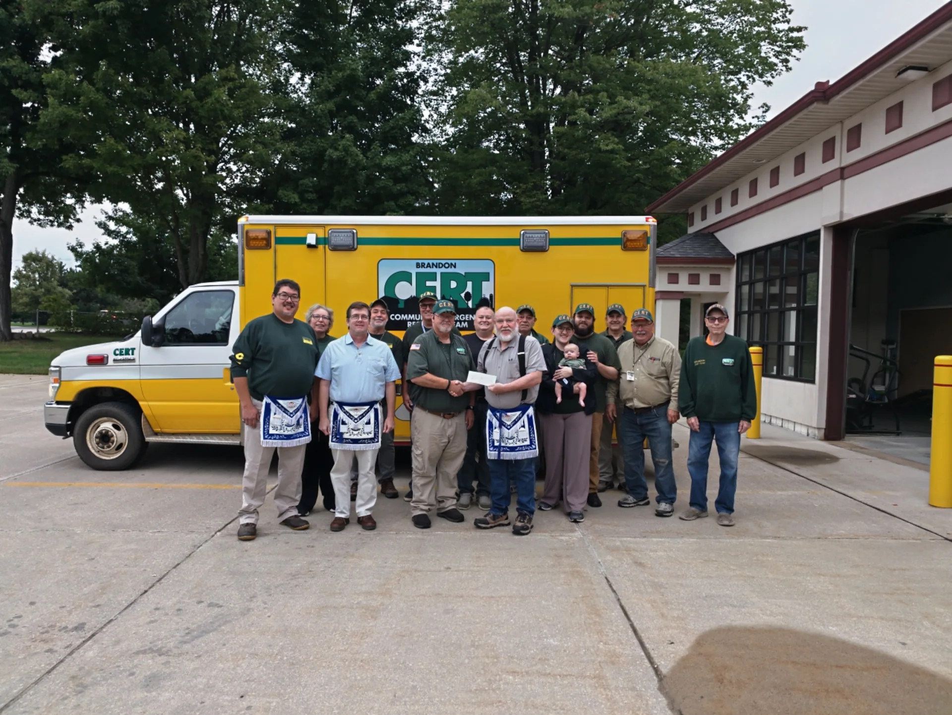 Team members and visitors gathered beside the Brandon CERT vehicle outside the fire station